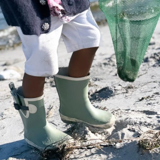 Gummistøvler, paraply og fiskenet – klar til leg ved vandet.